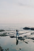 files/person-stands-on-rocks-poking-out-of-the-ocean-shoreline.avif